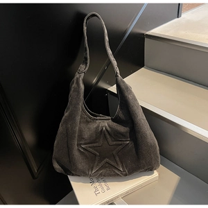 Detail of washed denim tote bag featuring a 3D embossed star and hobo style structure