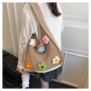 Detailed view of hand-knitted beige tote bag featuring 3D colorful crochet floral patterns