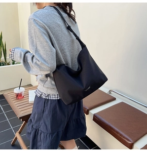Detail of a black oversized dumpling bag shown on shoulder for daily casual commute