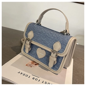 Close-up of heart-shaped fashion leather tag and denim stitching on the mini square bag