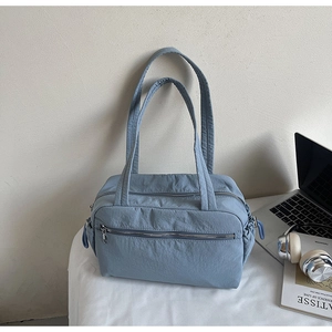 Detailed close-up of light blue nylon tote bag with dual straps and front zipper pocket