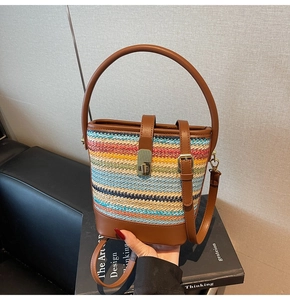 Detail of colorful woven bucket bag featuring brown leather trim and golden metal lock