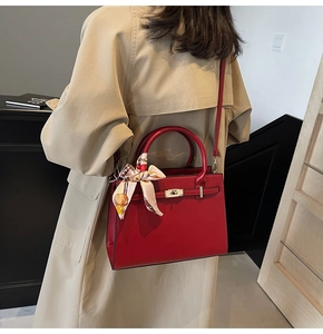 Detail of red leather wedding handbag featuring a metal lock and decorative silk scarf