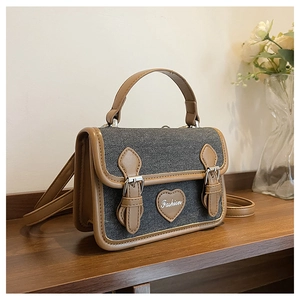 Detail view of denim texture crossbody bag with heart patch and vintage metal buckles