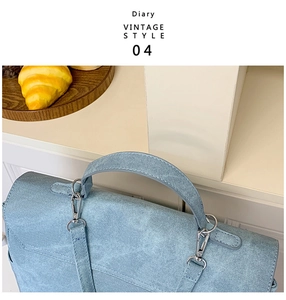 Detail of silver metal clasp and handle on a light blue denim texture vintage bag