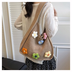 Detail of hand-crocheted floral appliques on a brown knit tote bag for women