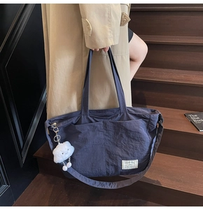 Détail du grand sac cabas en nylon bleu marine avec breloque et sangle tissée