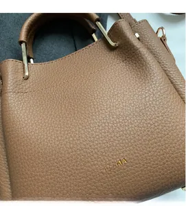 Detailed side view of caramel brown lychee leather handbag with gold metal handle hardware