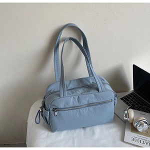 Detail of blue nylon tote bag with side drawstring pockets and front zipper pocket