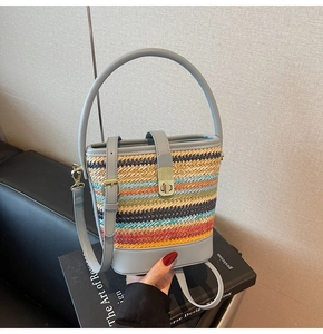 Close-up of multicolor woven straw bucket bag featuring a light blue leather strap and gold lock