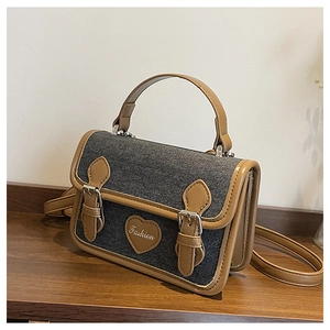 Detail of vintage denim crossbody bag with brown leather trim and heart fashion patch