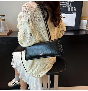 Détail du sac sous le bras noir rectangulaire avec texture en cuir plissé vintage
