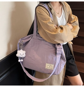 Grand sac de voyage en nylon violet porté par un mannequin avec un porte-clé nuage