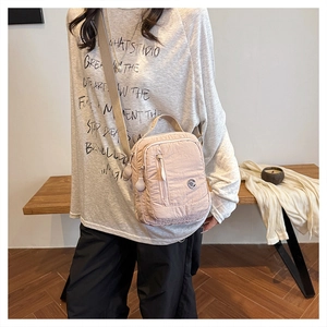 Detail of lightweight multi-pocket nylon crossbody bag with adjustable strap and top handle