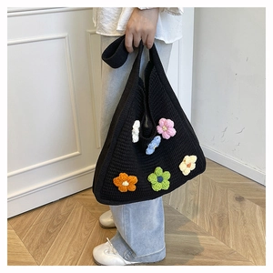 Detail of a black knit tote bag featuring colorful 3D handmade flowers and thick texture