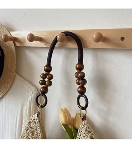 Detail of woven tote bag strap featuring dark wooden beads and brown cotton cords