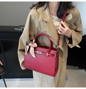 Close-up of red leather tote bag with gold lock and printed scarf handle detail