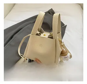 Detail of lychee pattern leather tote bag with round logo and cute plush sheep charm