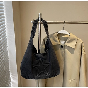 Detail of black denim hobo bag featuring embossed star pattern and washed texture