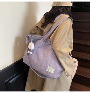 Détail d'un grand sac fourre-tout violet avec pendentif nuage en peluche sur un escalier