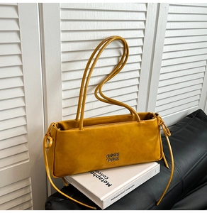 Détail du sac baguette jaune moutarde avec nœud latéral et lettrage logo argenté brillant