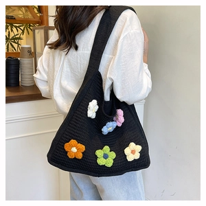 Detail of hand-crocheted black tote with colorful flower accents and wide shoulder strap