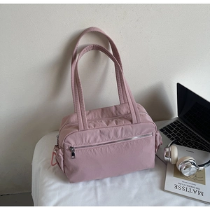 Macro shot of light pink tote bag showing utility pockets and smooth nylon texture