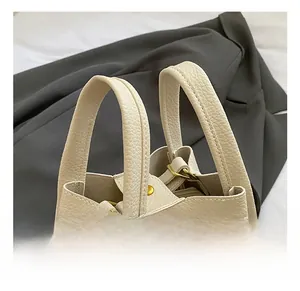 Detail of cream lychee leather handbag handles with gold hardware and plush charm