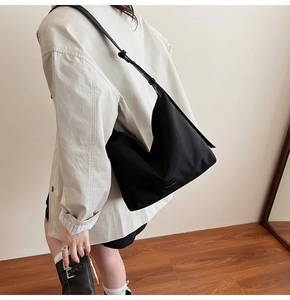 Detail of a large black minimalist hobo shoulder bag with an adjustable wide strap