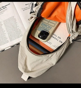 Detail view of beige nylon crossbody bag with orange lining showing interior capacity
