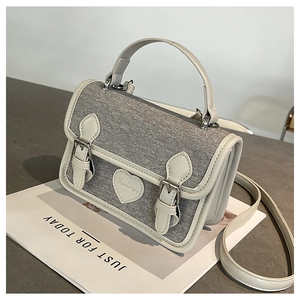 Detail of grey denim texture and heart patch on a stylish crossbody handbag