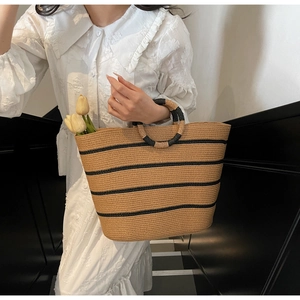 Close-up of handmade woven straw tote bag with black stripes and unique round handle