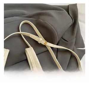Close-up of adjustable beige lychee leather shoulder strap with gold-tone buckle hardware