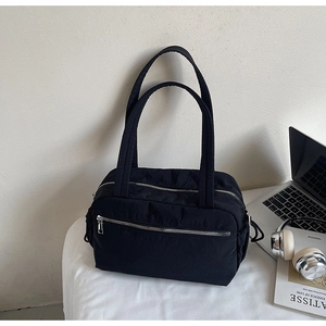 Detail of black nylon tote bag with functional silver zippers and multiple pockets