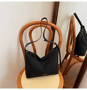 Close-up of sleek black nylon tote featuring silver GLEAMX metal logo and zipper detail