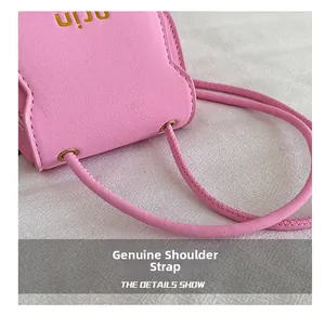 Close-up of pink litchi leather bag showing shoulder strap connection and gold lettering