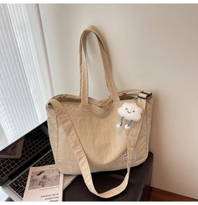 Détail du cabas en toile beige avec breloque nuage en peluche et bandoulière longue