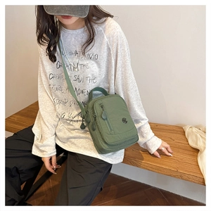 Army green nylon crossbody bag with multi-pocket design shown worn on a casual model