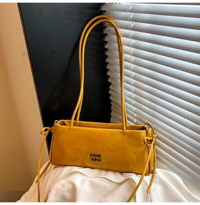 Détail du sac baguette en cuir jaune montrant la texture fine et les nœuds décoratifs