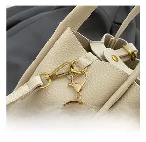 Detail of cream lychee leather handbag featuring golden metal hook and ring buckle