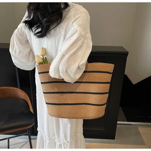 Close-up of large straw tote bag with black stripes and tulips for beach holiday