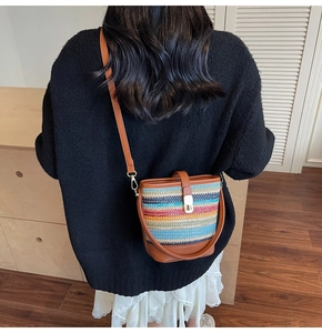Detail view of woven bucket bag featuring colorful patterns and brown leather straps