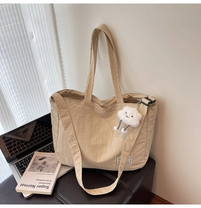 Détail du sac de voyage beige grande capacité avec bandoulière et breloque nuage doux
