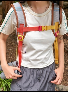 Sac à dos extérieur avec sangles rouges et jaunes porté par un randonneur en forêt