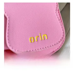 Detail of pink lychee leather mini saddle bag with white stitching and orin logo