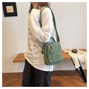 Close-up of the light green nylon multi-pocket crossbody bag with adjustable shoulder strap