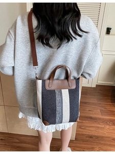 Vertical striped canvas tote bag with brown leather trim and adjustable shoulder strap