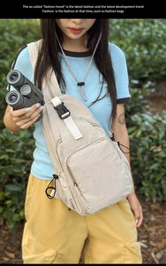 Detail of light beige nylon crossbody chest bag with adjustable white strap on a model