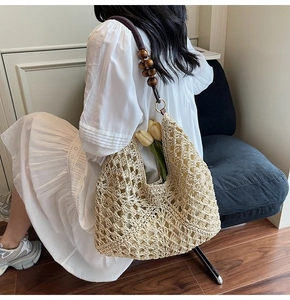 Detail of woven straw tote bag featuring diamond pattern and decorative wooden beads
