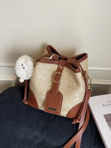 Straw woven bucket bag with brown leather trim and cute white plush charm accessory